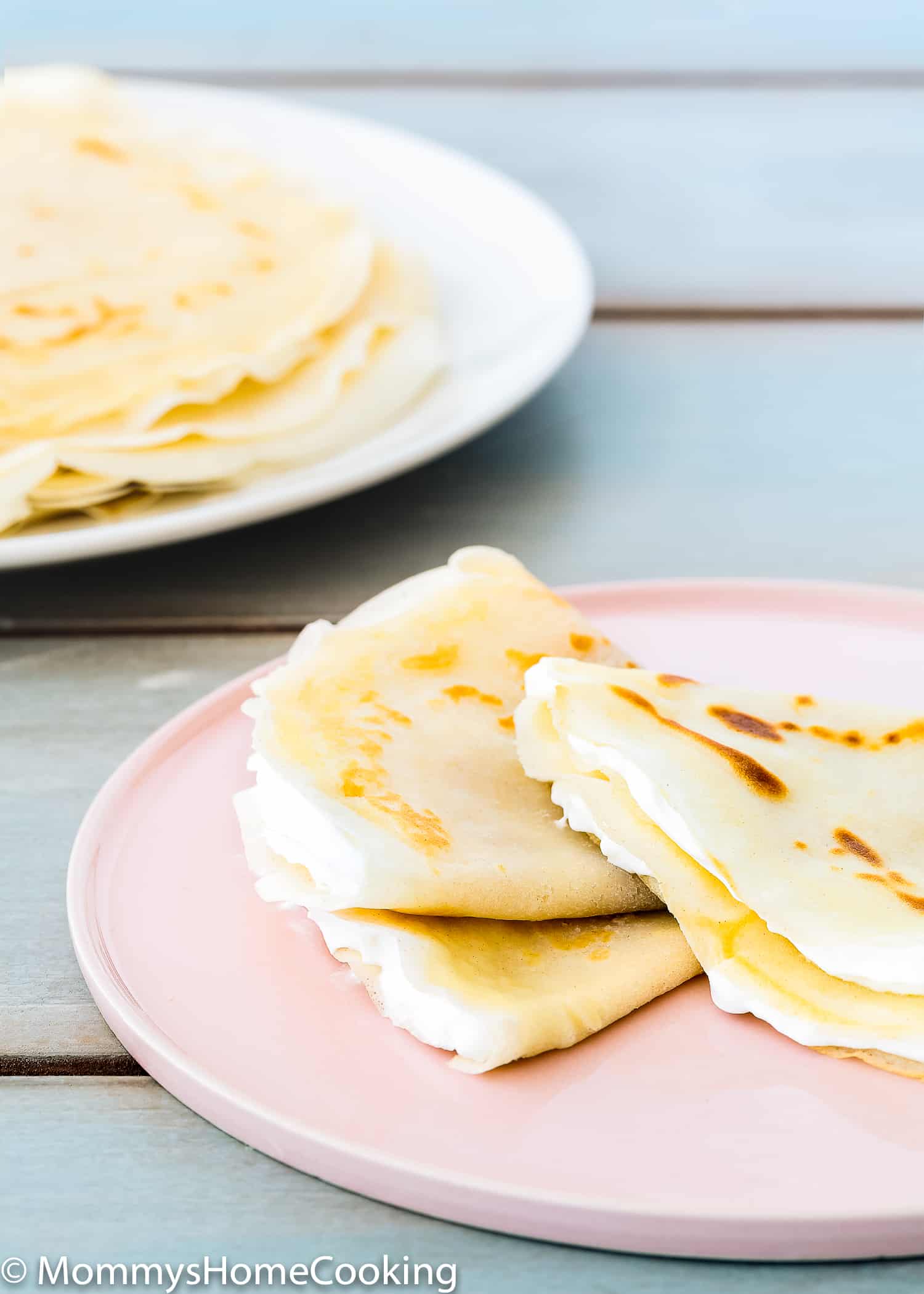 A pink plate with three folded egg-free crepes on it.