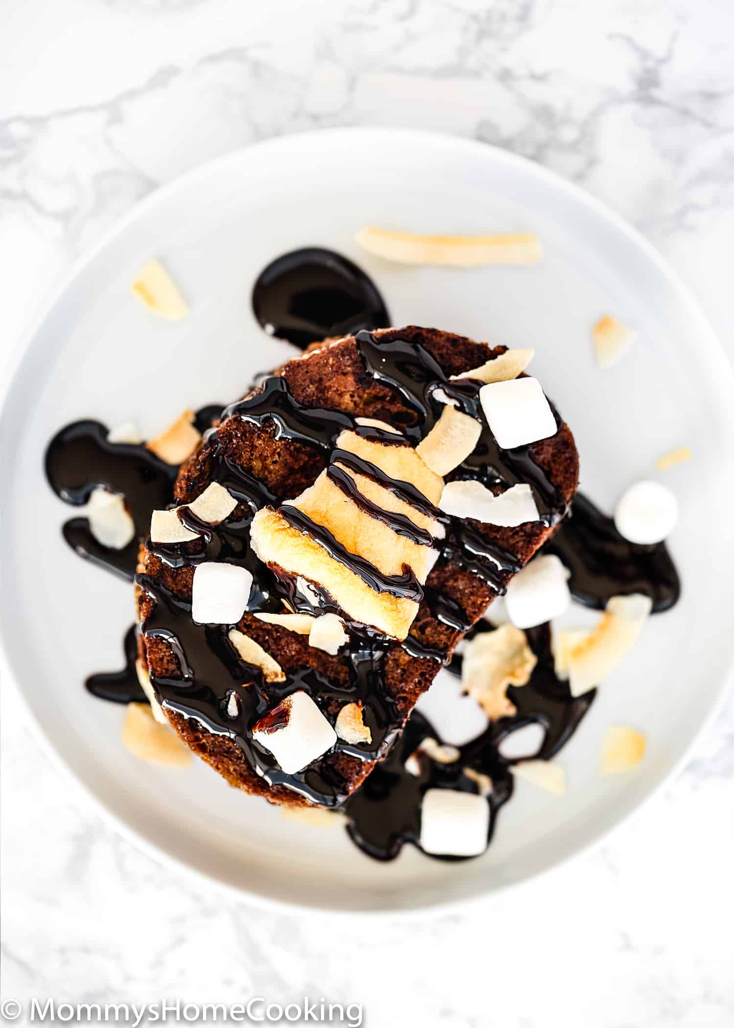 Eggless Chocolate French Toast on a plate with chocolate sauce, coconut, and marshmallows.