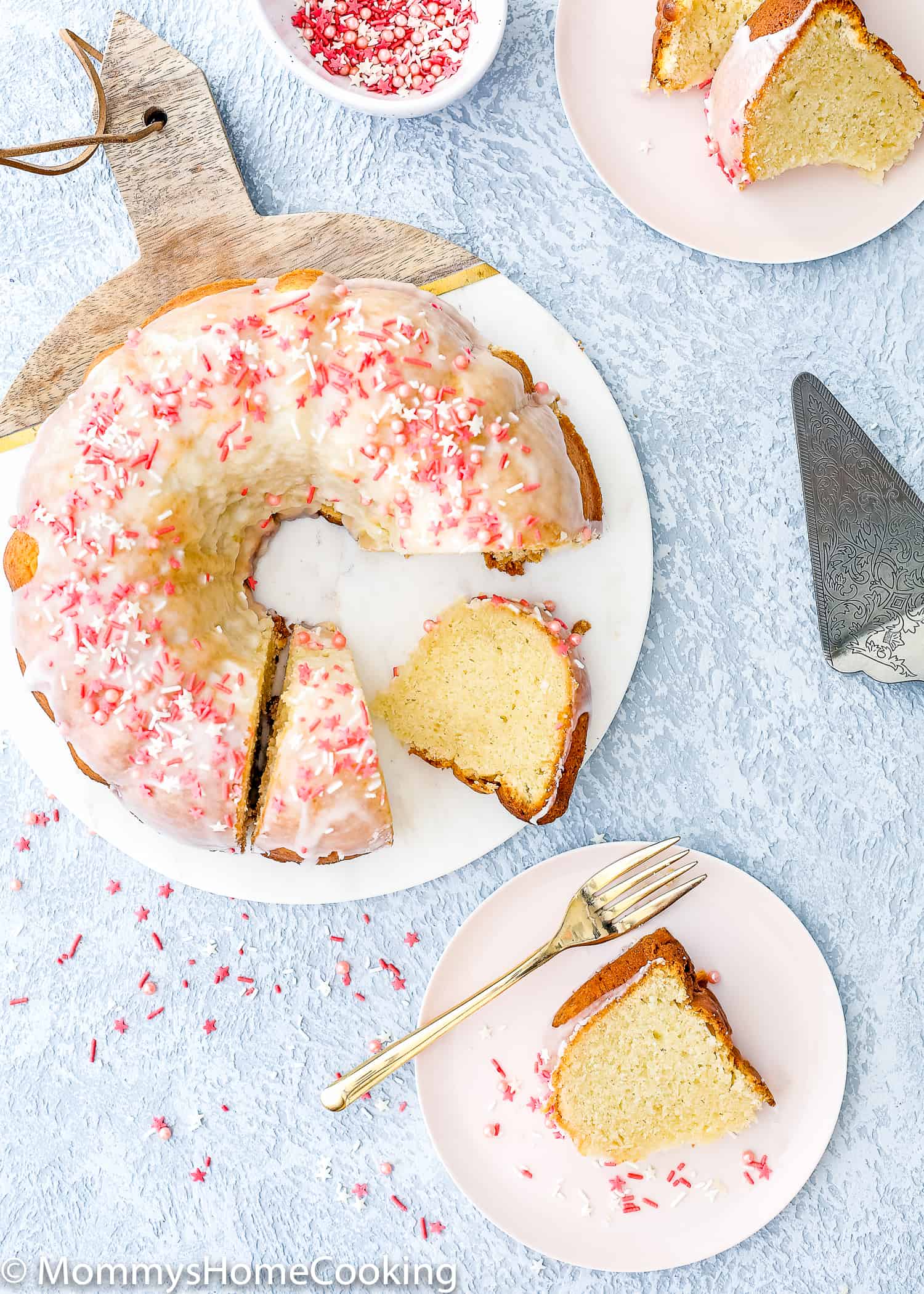 Eggless Vanilla Pound Cake over a blue table with a pink plate and a cake server on the side. 