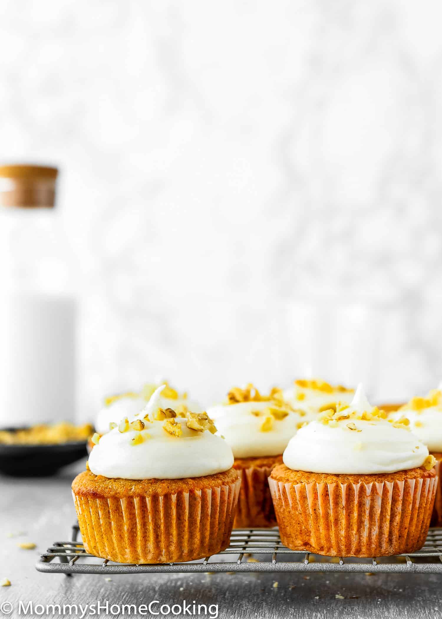 Eggless Carrot Cake Cupcakes with frosting over a cooling rack 