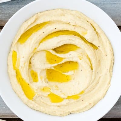 homemade mustard hummus in a bowl with olive oil on top.