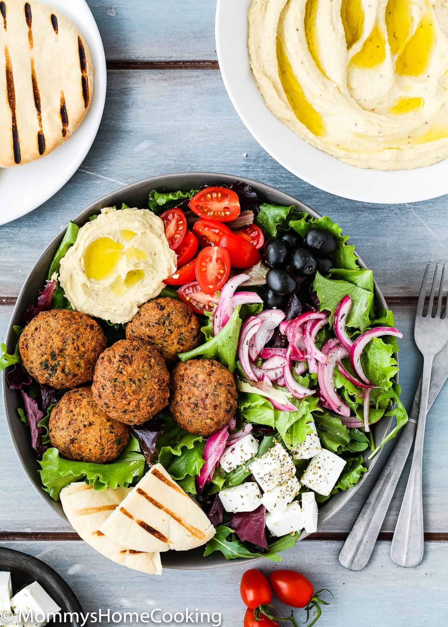 Falafel Salad Bowls with Hummus over a blue wooden surface. 