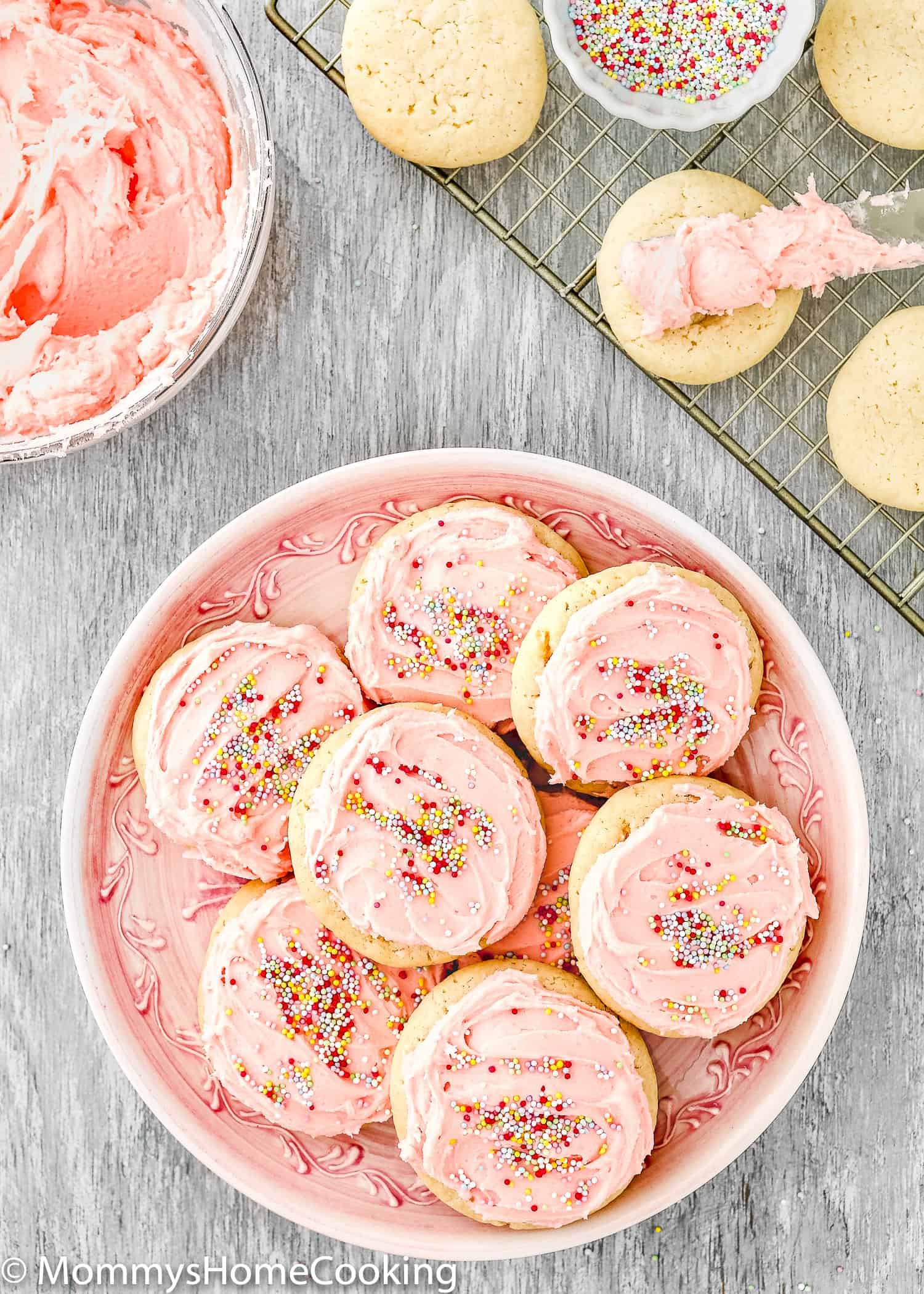 A plate with eggless sugar cookies frosted with pink buttercream and sprinkle.