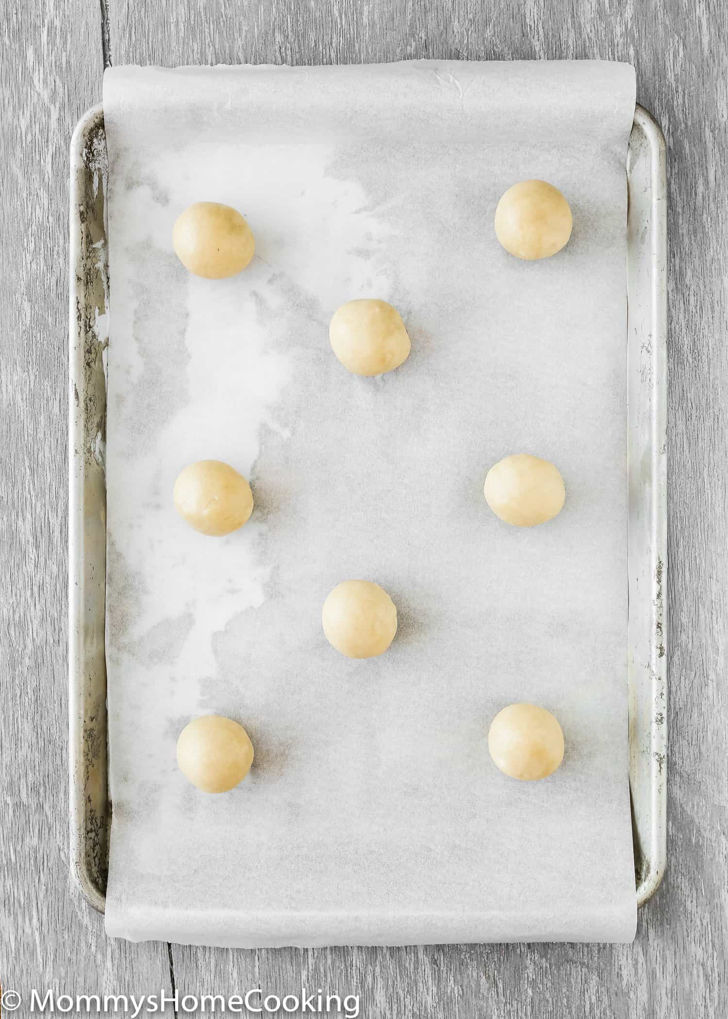 Eggless sugar cookie dough rolled into balls in a baking sheet