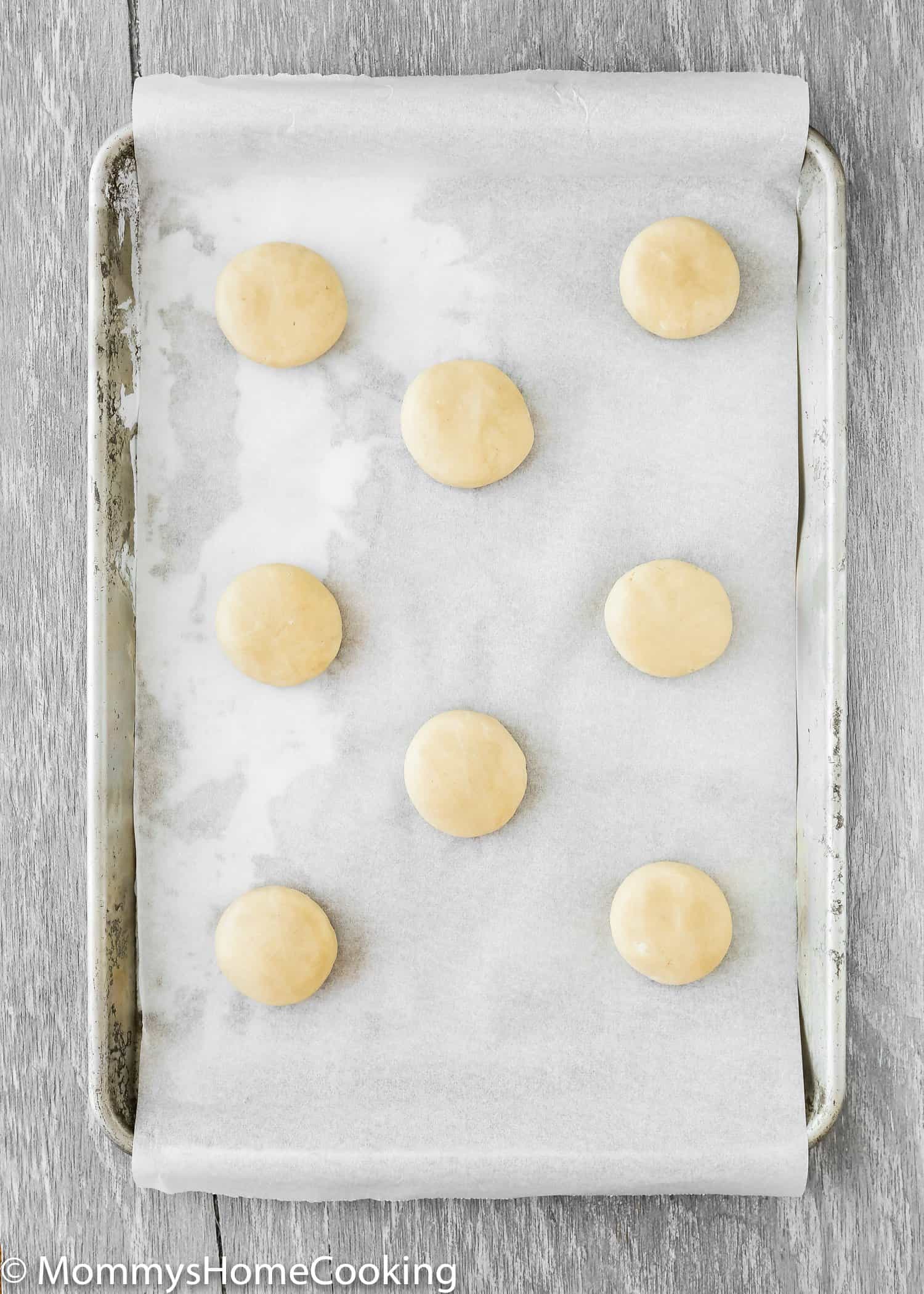 Eggless sugar cookie dough flattened balls in a baking sheet