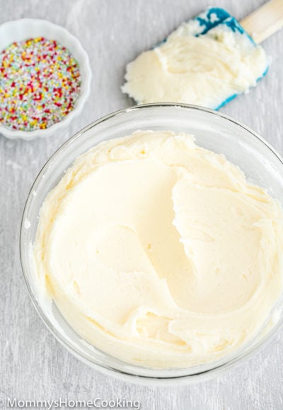 Vanilla Buttercream Frosting in a bowl with sprinkles and a spatula on the sides