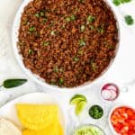 Cooked Ground Beef for Tacos in a skillet surrounded by taco toppings