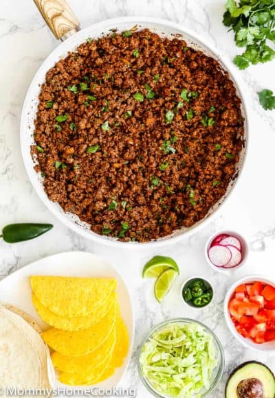 Cooked Ground Beef for Tacos in a skillet surrounded by taco toppings