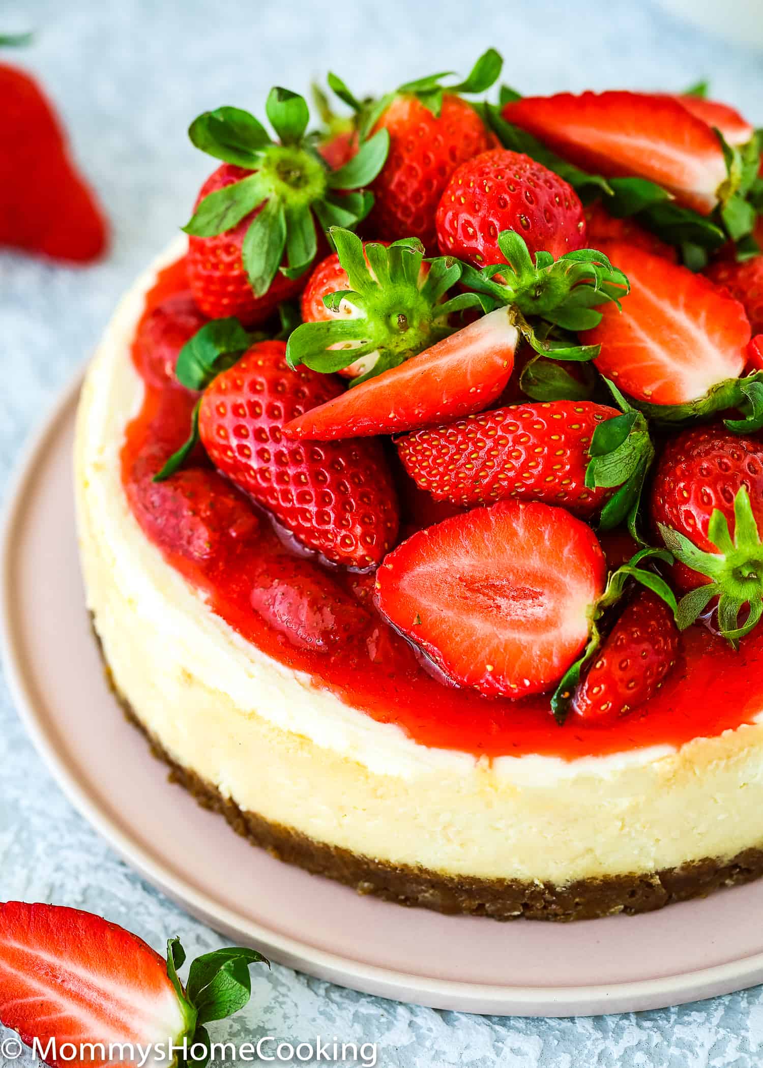 an egg-free cheesecake made in the instant pot on a pink serving plate with fresh strawberries on top.