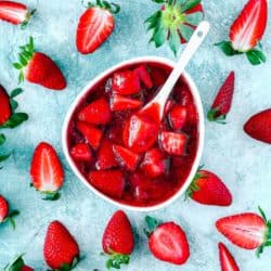 Strawberry sauce/topping in a white bowl and fresh strawberries