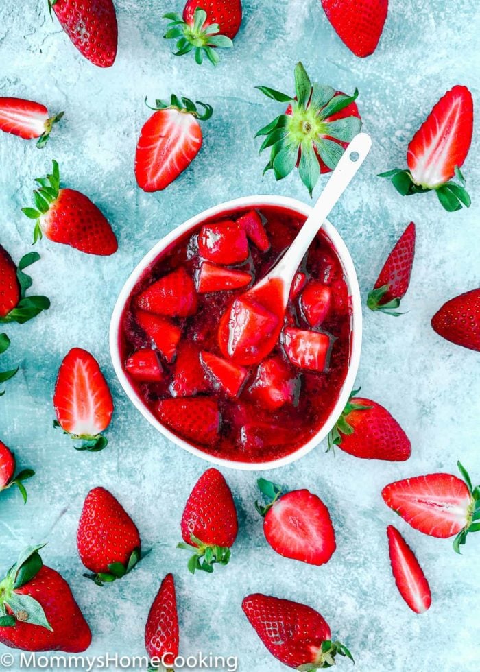 Strawberry sauce/topping in a white bowl and fresh strawberries