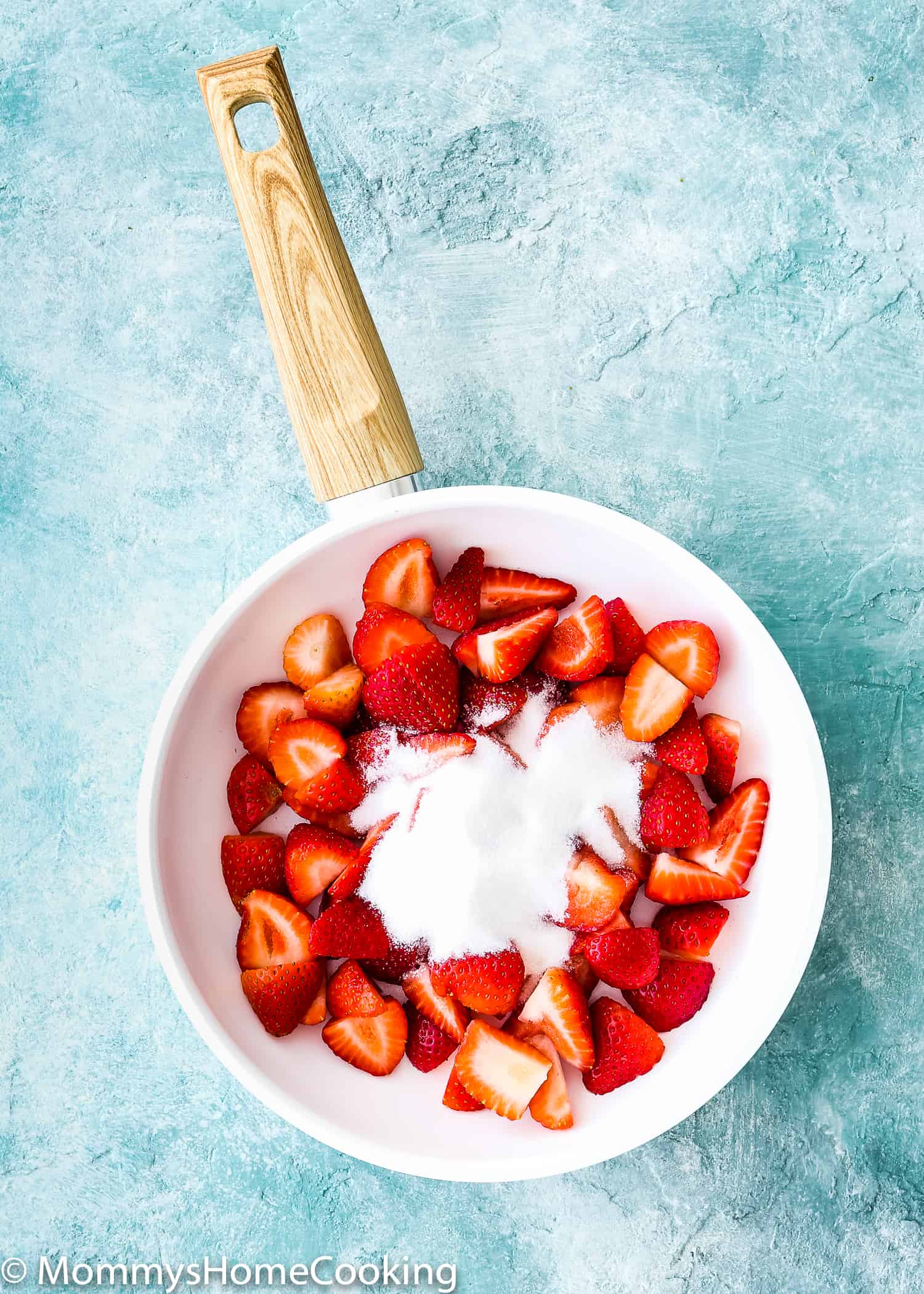 white skillet with chopped strawberries and sugar