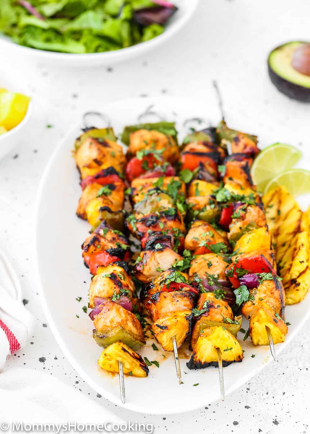 Easy Grilled Hawaiian Chicken Skewers in a white plate with lemon wedges and grilled pineapple