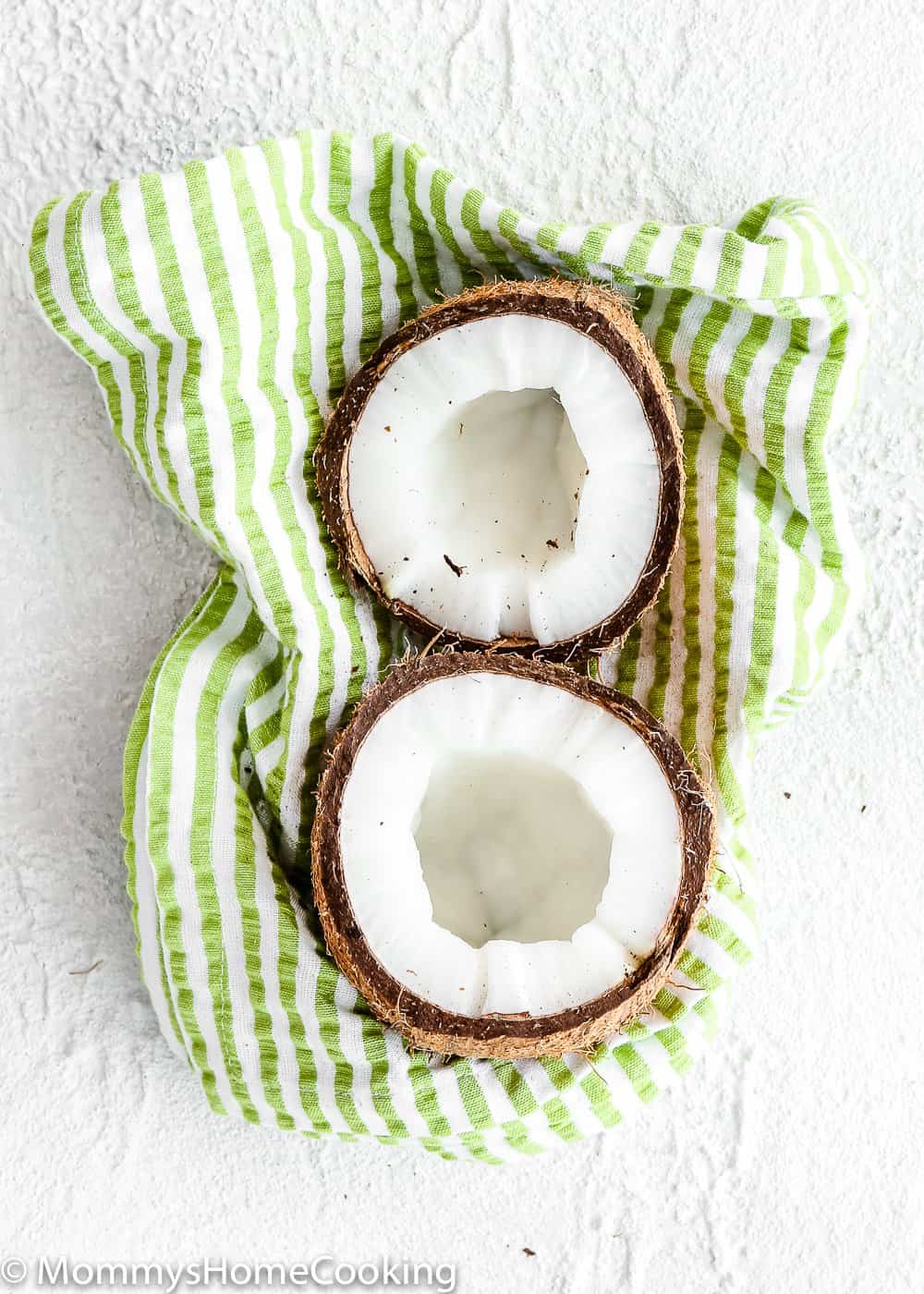 a crack open coconut over a kitchen towel.