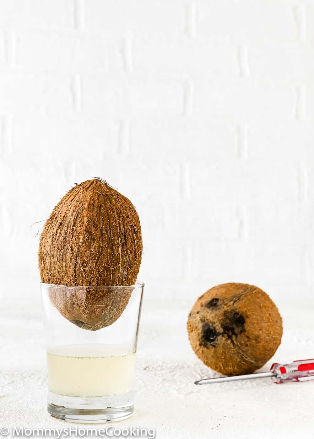 a coconut in a glass draining the water. 