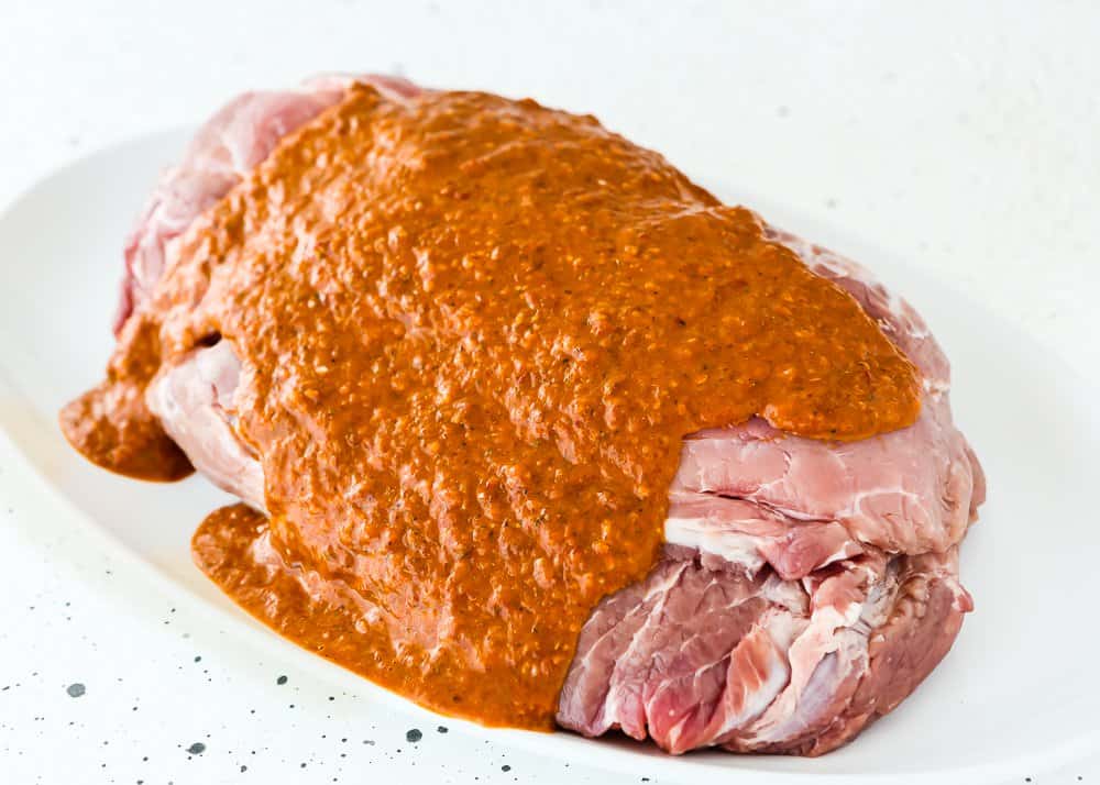 raw pork shoulder with chipotle sauce over it. 