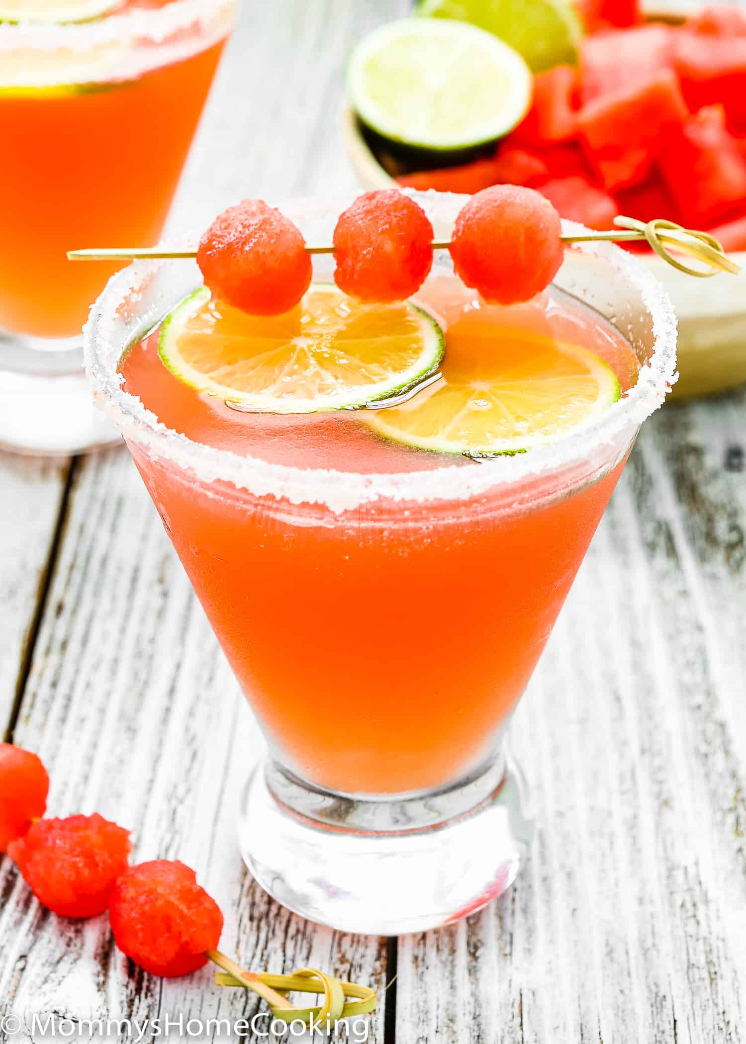 a Watermelon Cocktail in a cosmopolitan glass with watermelon balls and lime slices. 