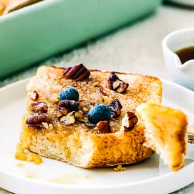 eggless french toast with, syrup, pecan and blueberries on top on a plate.