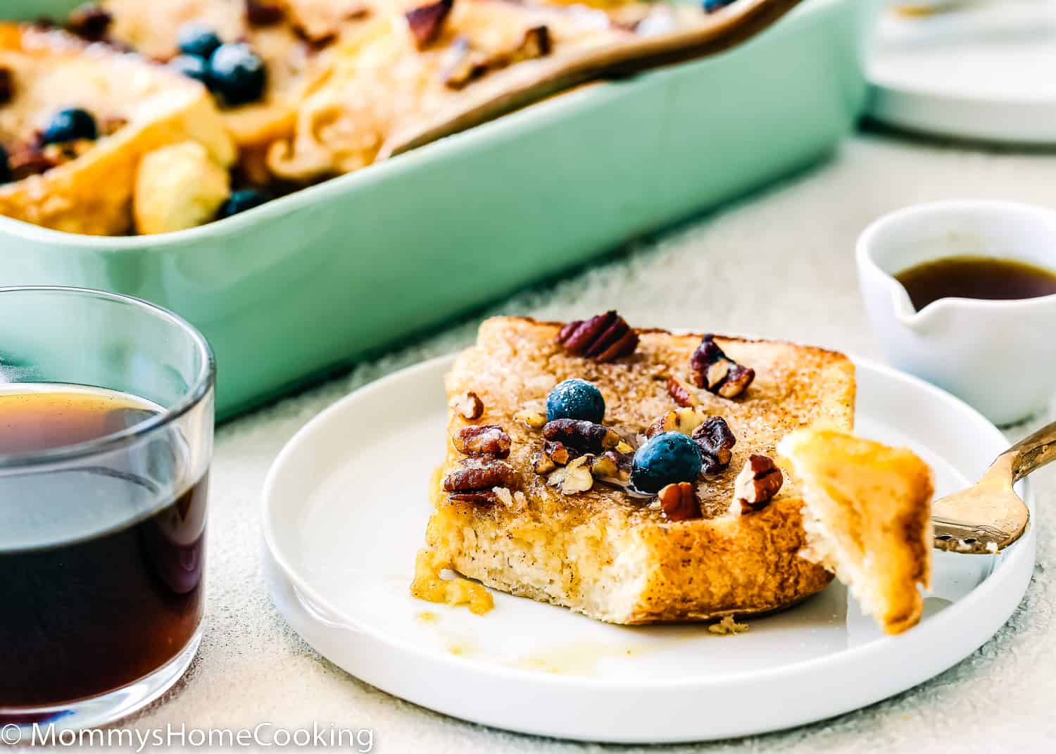 egg-free french toast with, syrup, pecan and blueberries on top on a plate and a cup of coffee on the side.