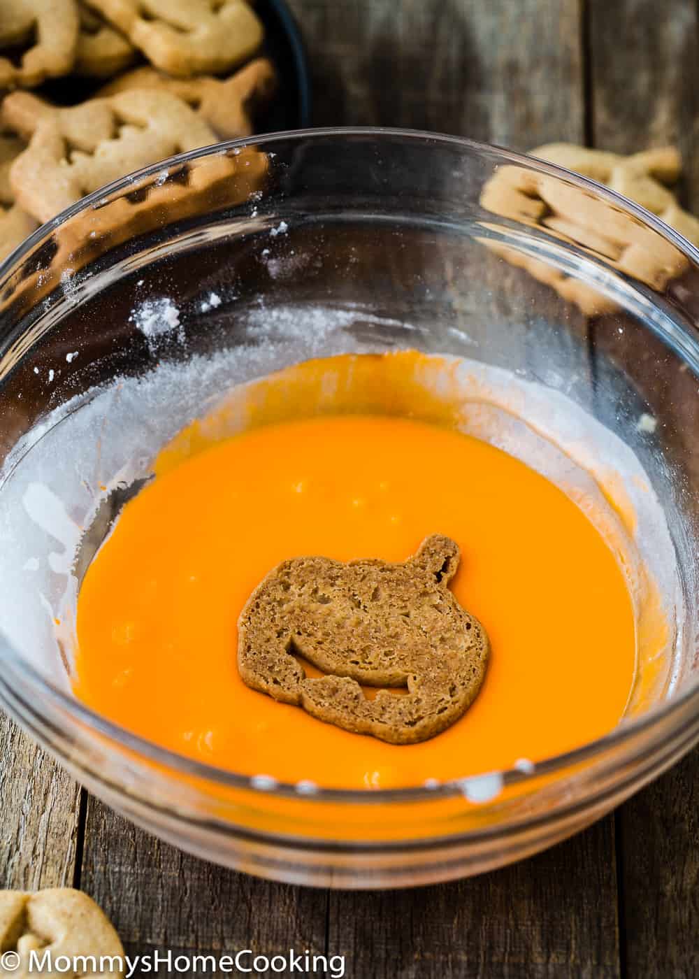 an eggless Jack-o'-lantern cookie in a bowl with cookie glaze. 
