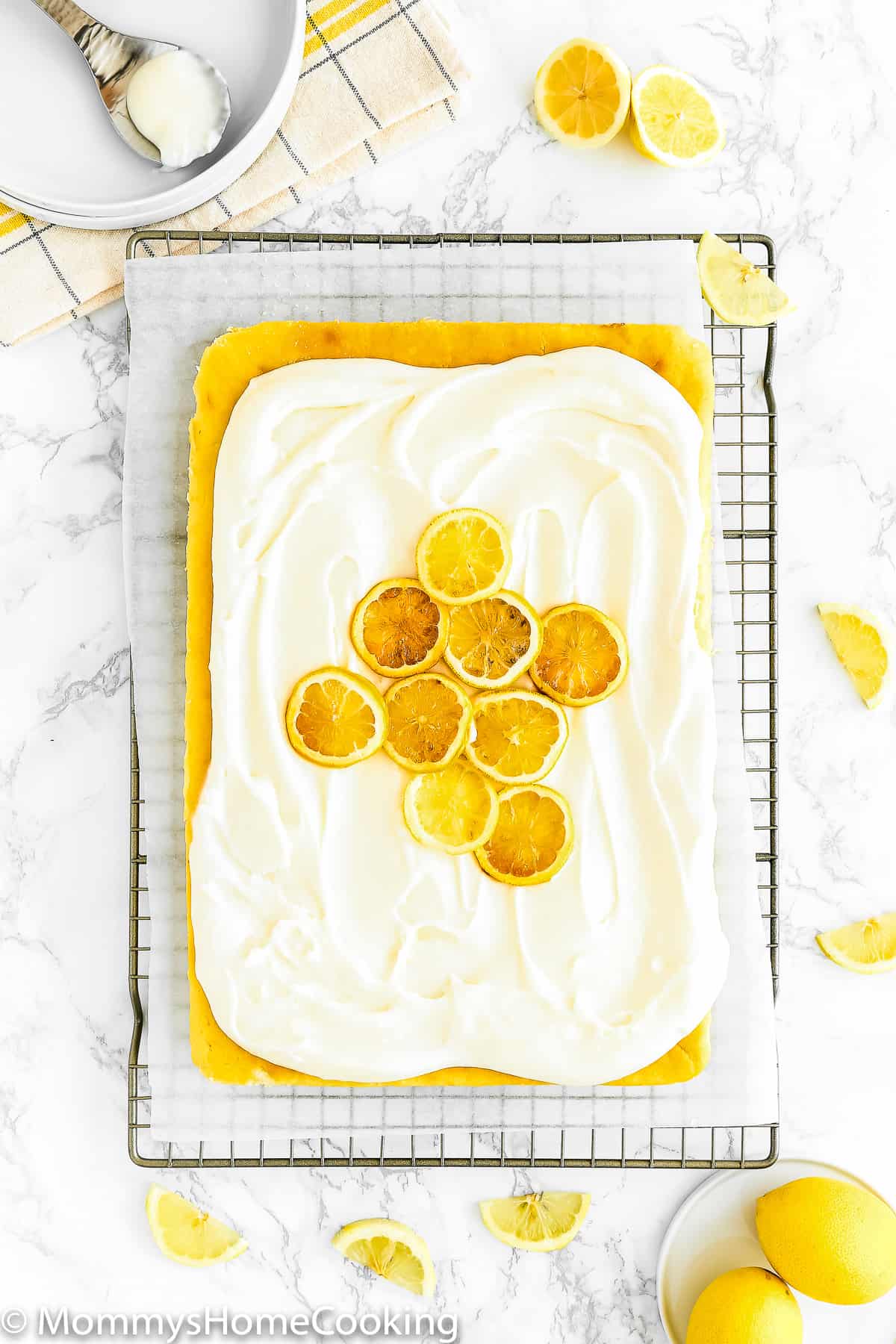 An Eggless Lemon Cake with buttercream and candied lemons over a cooling rack. 