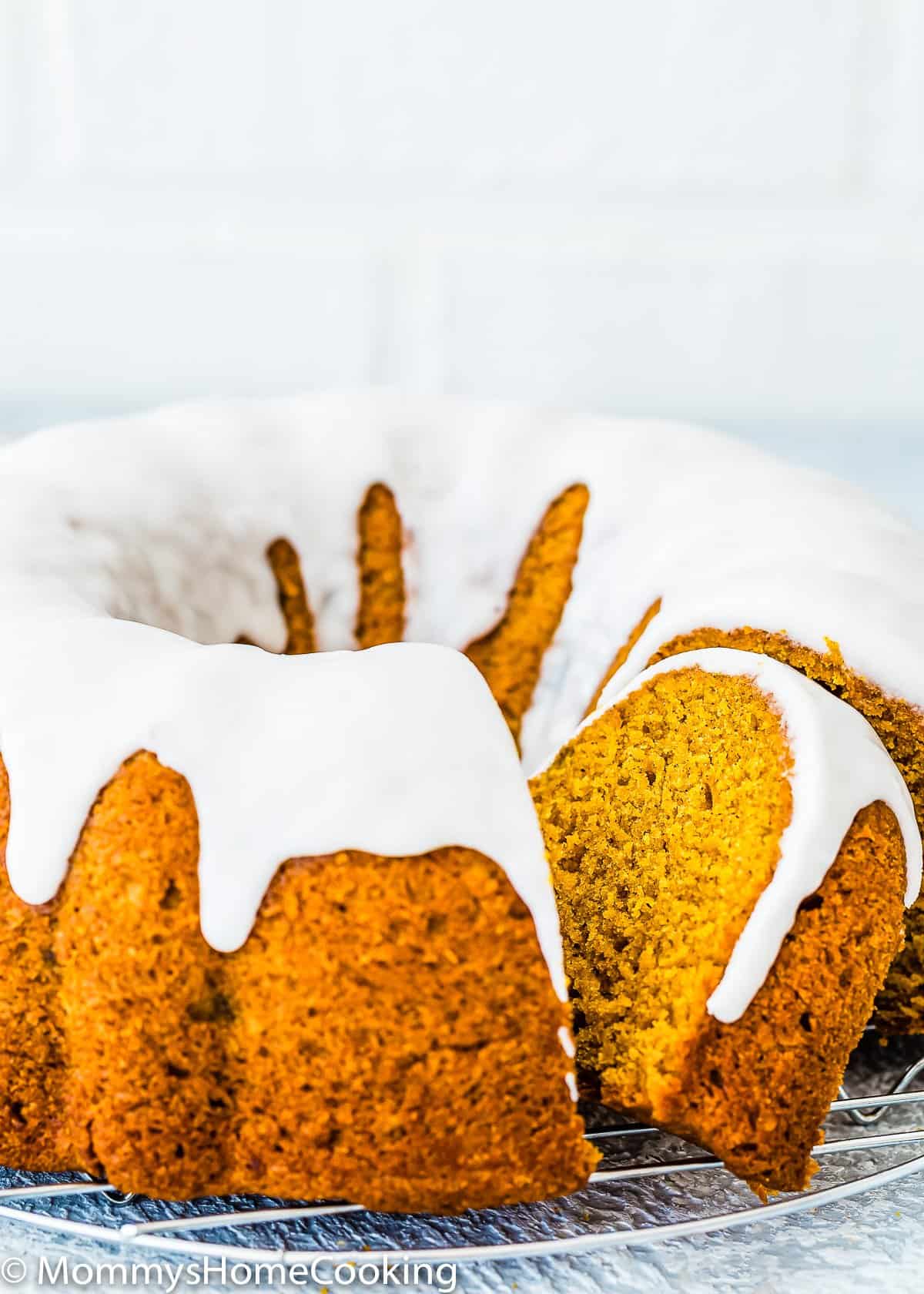 sliced Eggless Pumpkin Cake with glaze over a cooling rack.