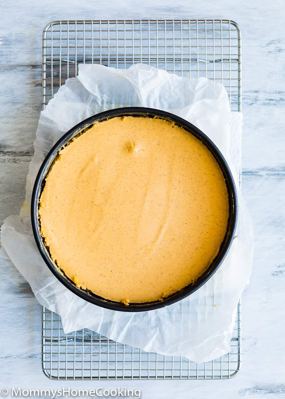 egg-free pumpkin Cheesecake in a springform pan over a cooling rack. 