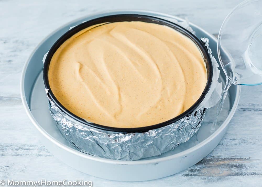 an unbaked egg-free pumpkin Cheesecake in a springform pan into a larger pan with boiling water. 