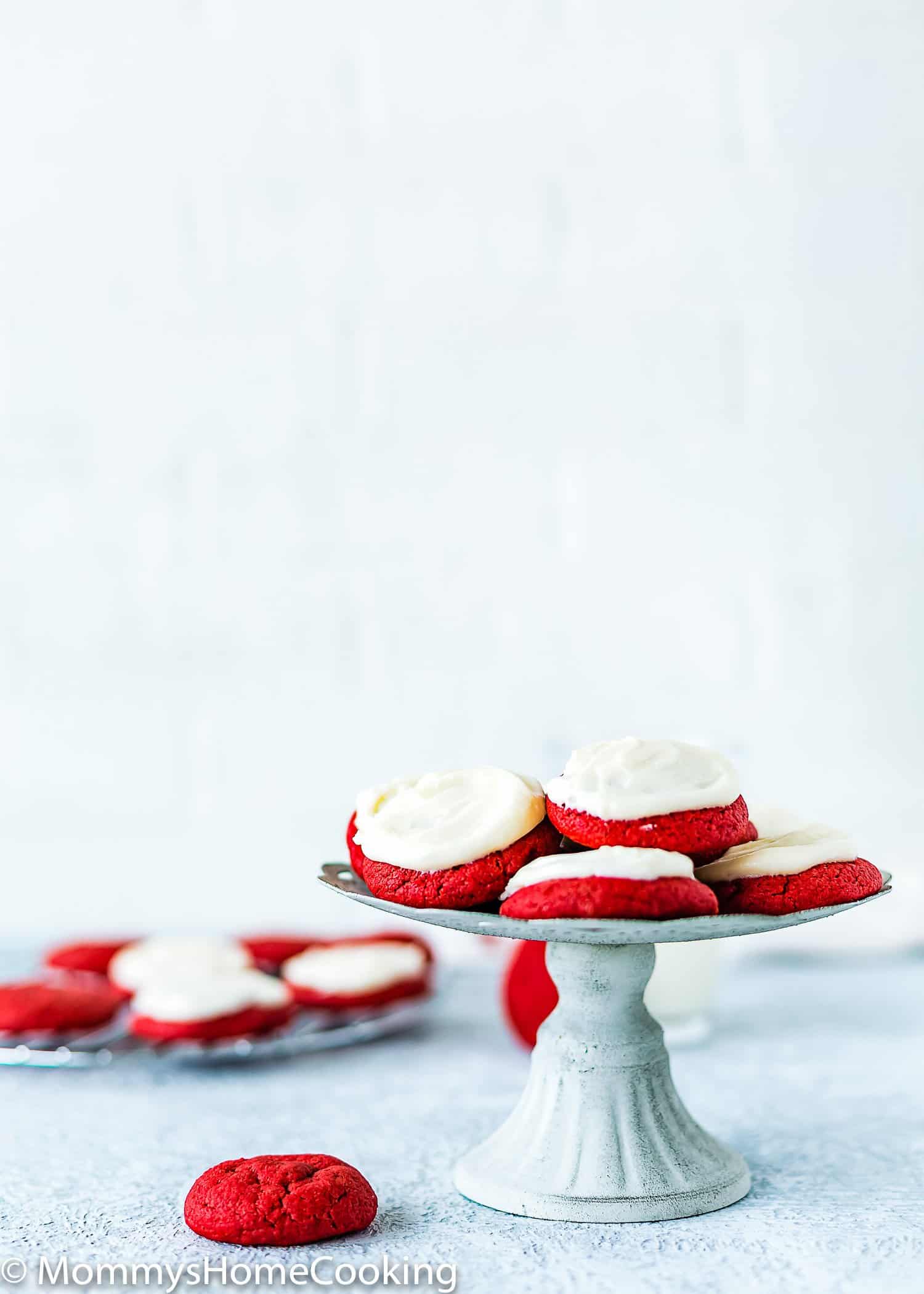 eggless red velvet cookies with cream cheese frosting on a metal cake stand