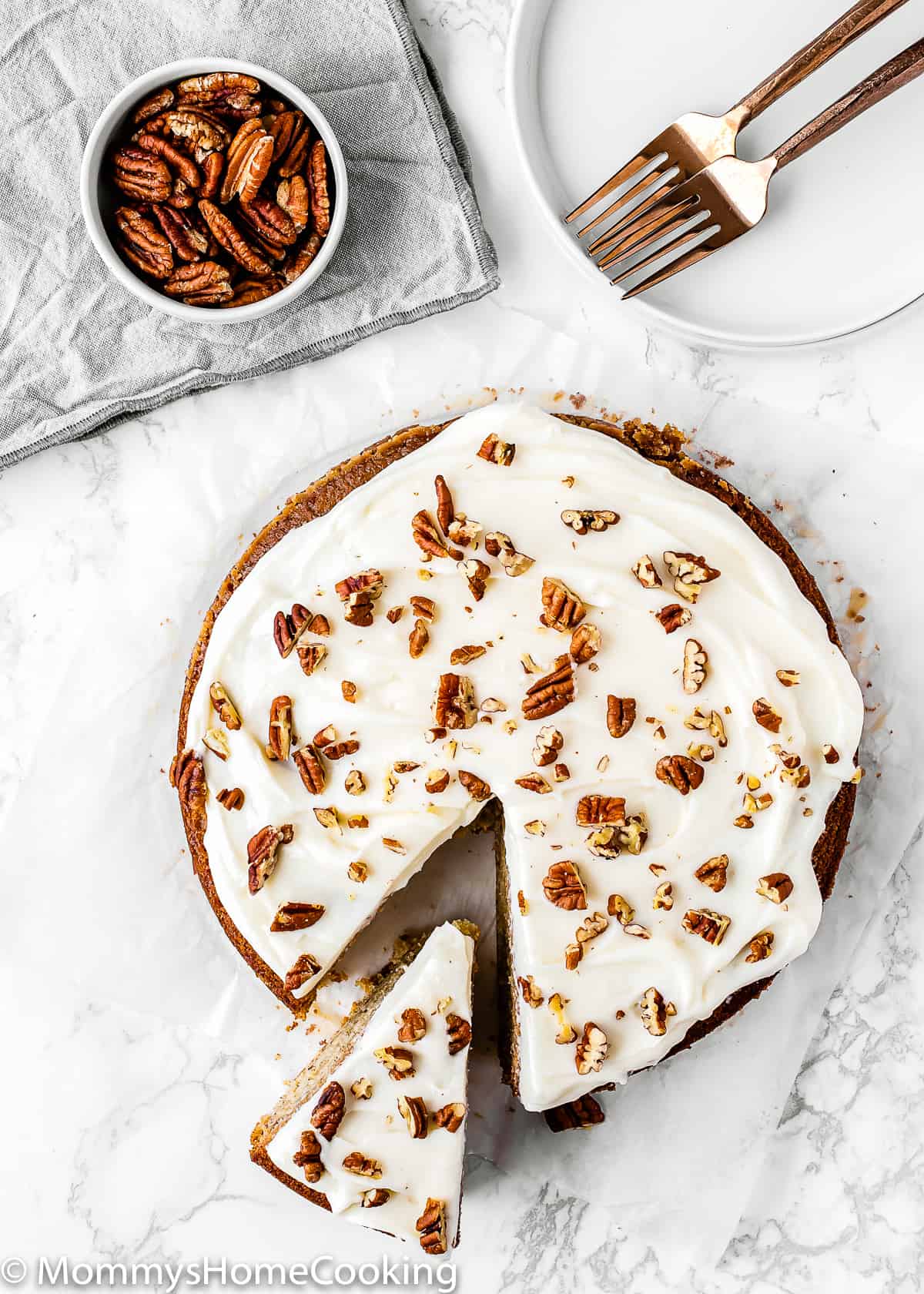 overhead view of an Eggless Banana Cake with frosting and roasted pecans