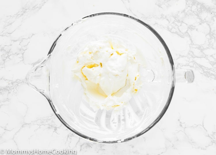 Cream cheese and sour cream beat together in a stand mixer bowl.