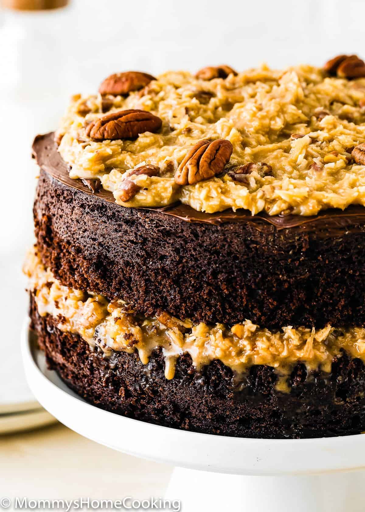 Eggless German Chocolate Cake in a cake stand closeup.