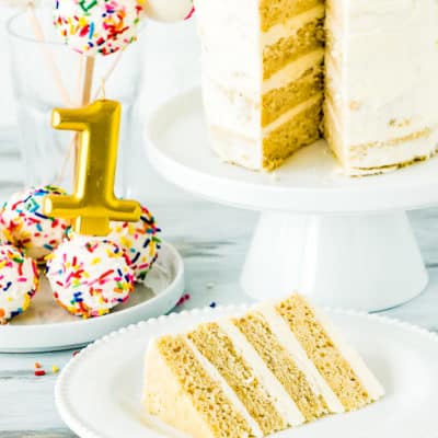 eggless smash cake sliced with cake pops and a candle on the background