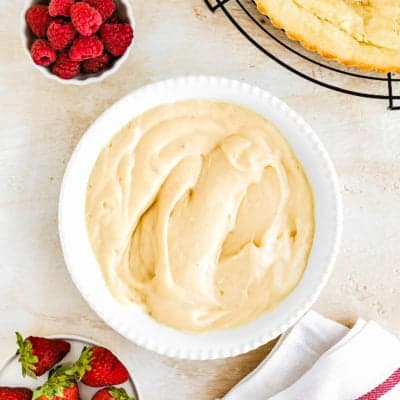 Eggless Pastry Cream in a bowl with fresh berries on the side and a egg-free tart crust.