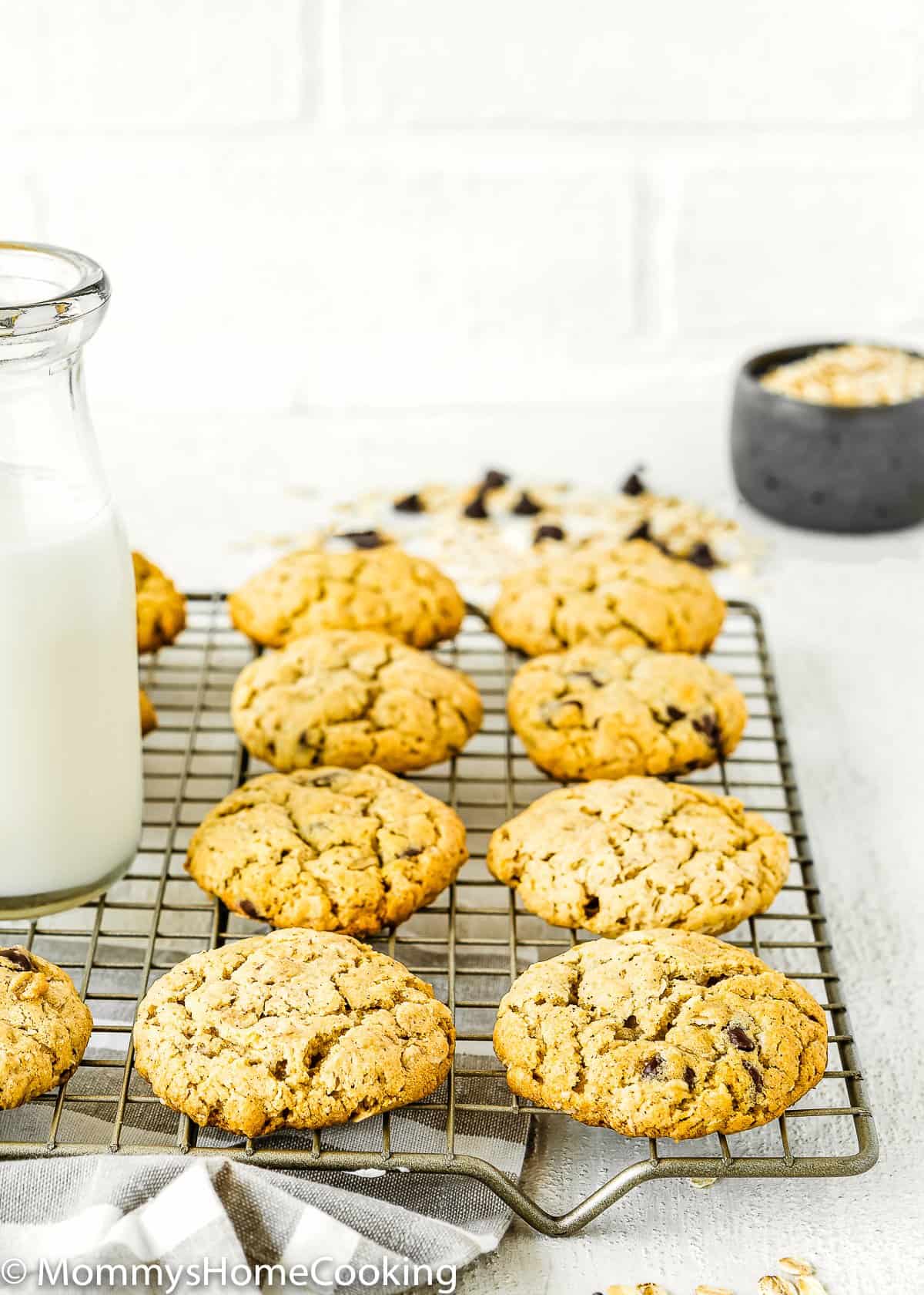 Eggless Oatmeal Cookies over a cooling rack with a bottle of milk.