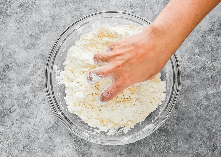 a hand cutting in the butter into the dry ingredients. 