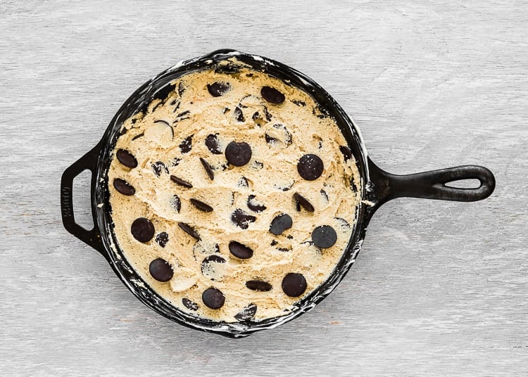 egg-free chocolate chip cookie dough evenly spread in skillet with chocolate chips on top.