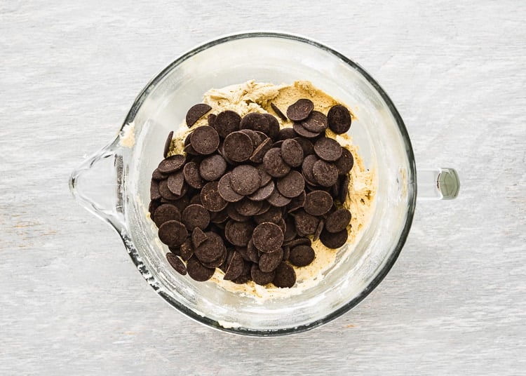 egg-free cookie dough in a bowl of a stand mixer with chocolate on top. 