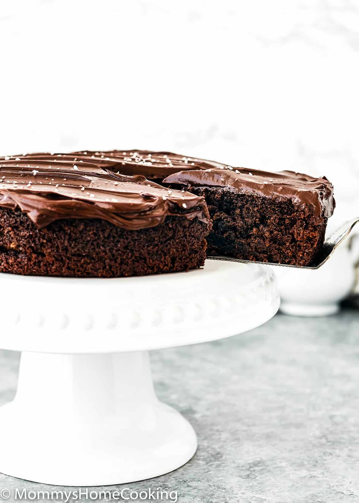 cake cutter holding a slice of One Bowl Eggless Chocolate Cake.