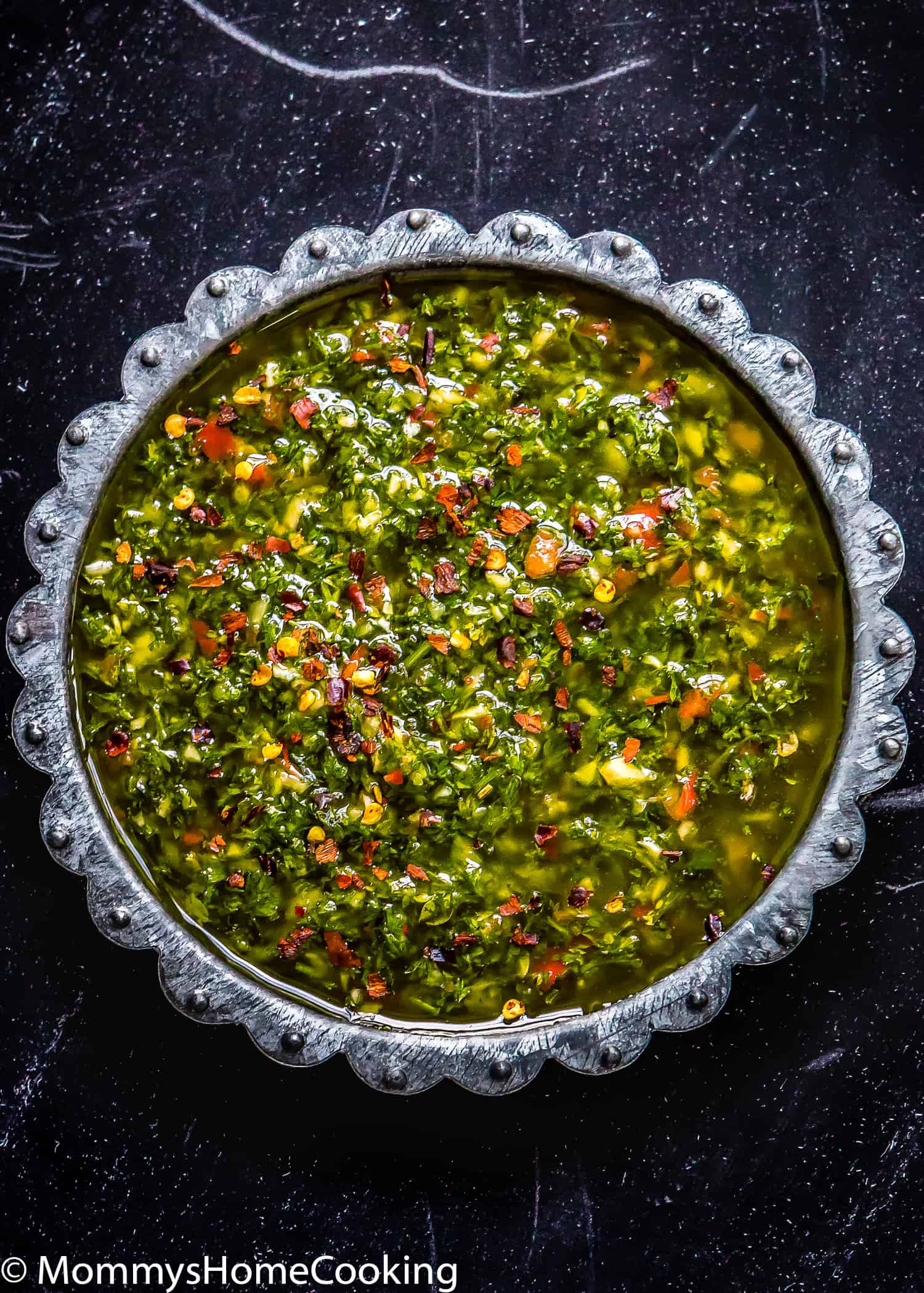 Chimichurri Sauce in a plate over a black surface.