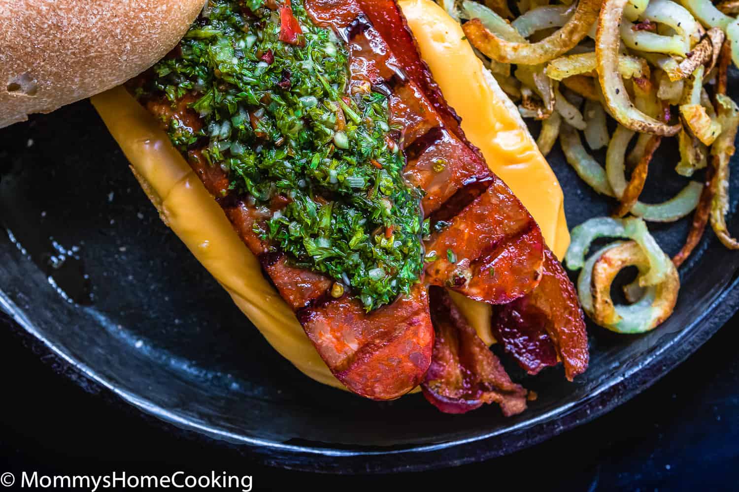 A hot dog with chimichurri sauce.
