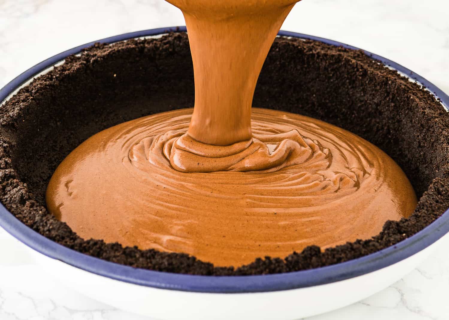 eggless chocolate pie filling being poured over a oreo crust. 