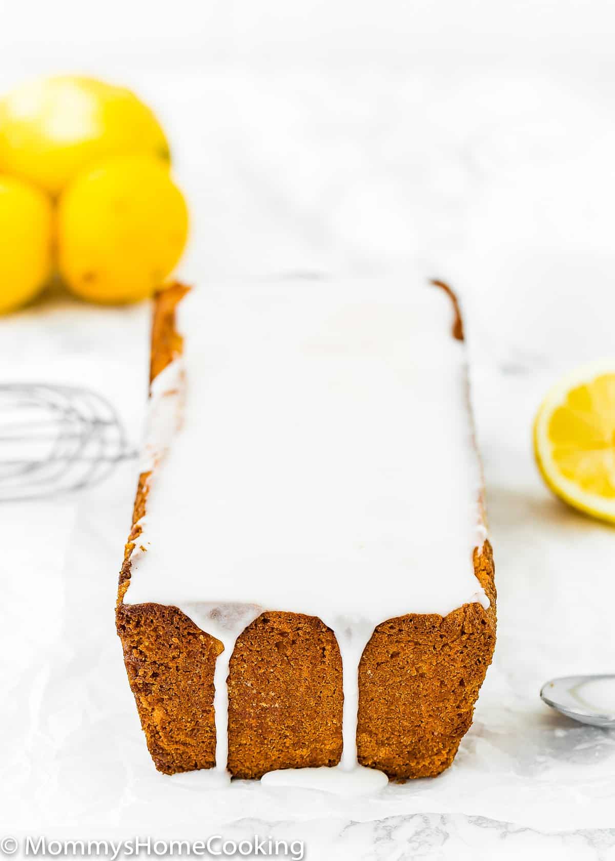 Eggless Lemon Pound Cake with glaze and fresh lemons on the background.