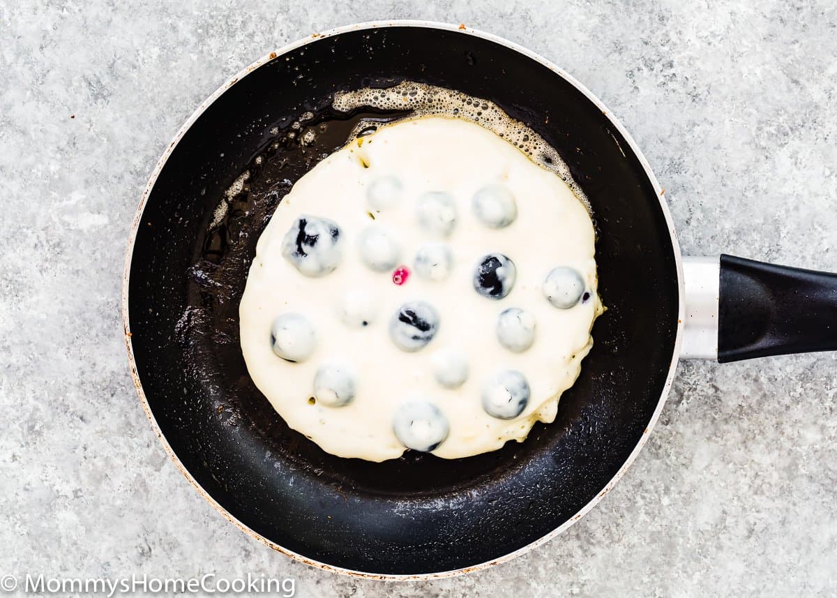 egg-free blueberry pancake cooking in a skillet