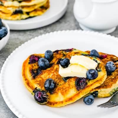 Eggless Blueberry Pancakes with fresh blueberries and butter in a plate