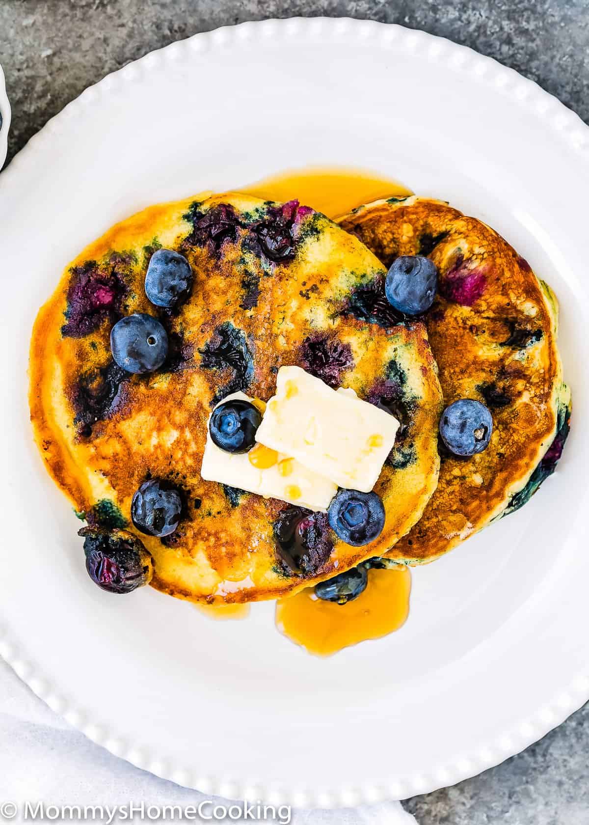 Eggless Blueberry Pancakes with fresh blueberries and butter in a plate.