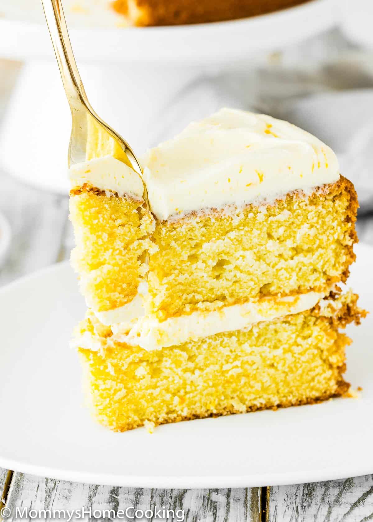Eggless Orange Cake slice on a plate with a fork.
