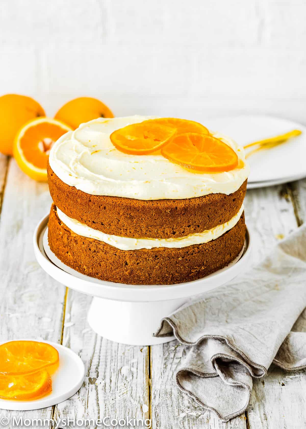 two layers Eggless Orange Cake with orange buttercream on a cake stand