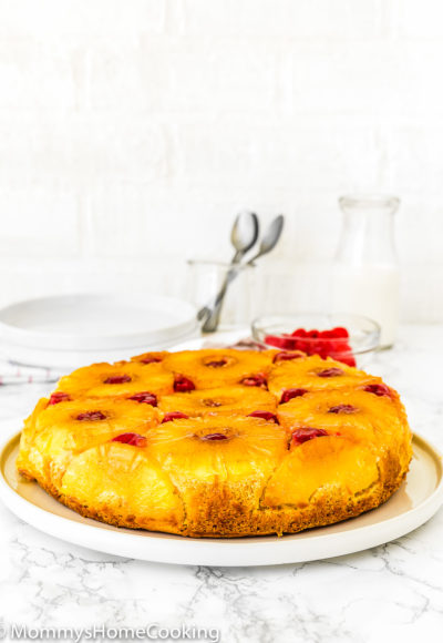 whole Eggless Pineapple Upside Down Cake on a plate over a marble surface