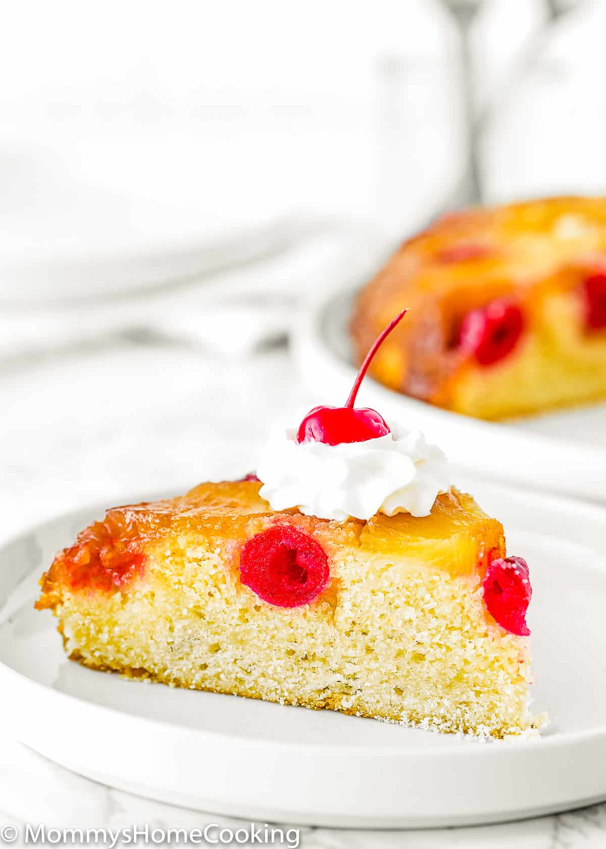 slice of Eggless Pineapple Upside Down Cake with whipped cream on a plate
